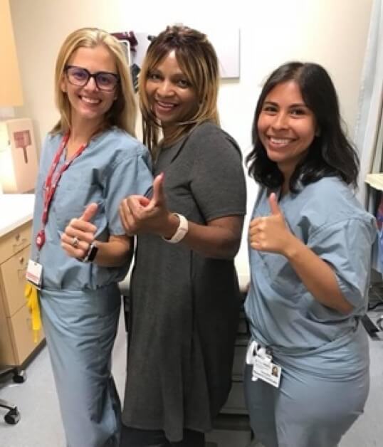 Sharon Rivera-Sanchez stands between two Penn Medicine employees, all of whom give a thumbs up.