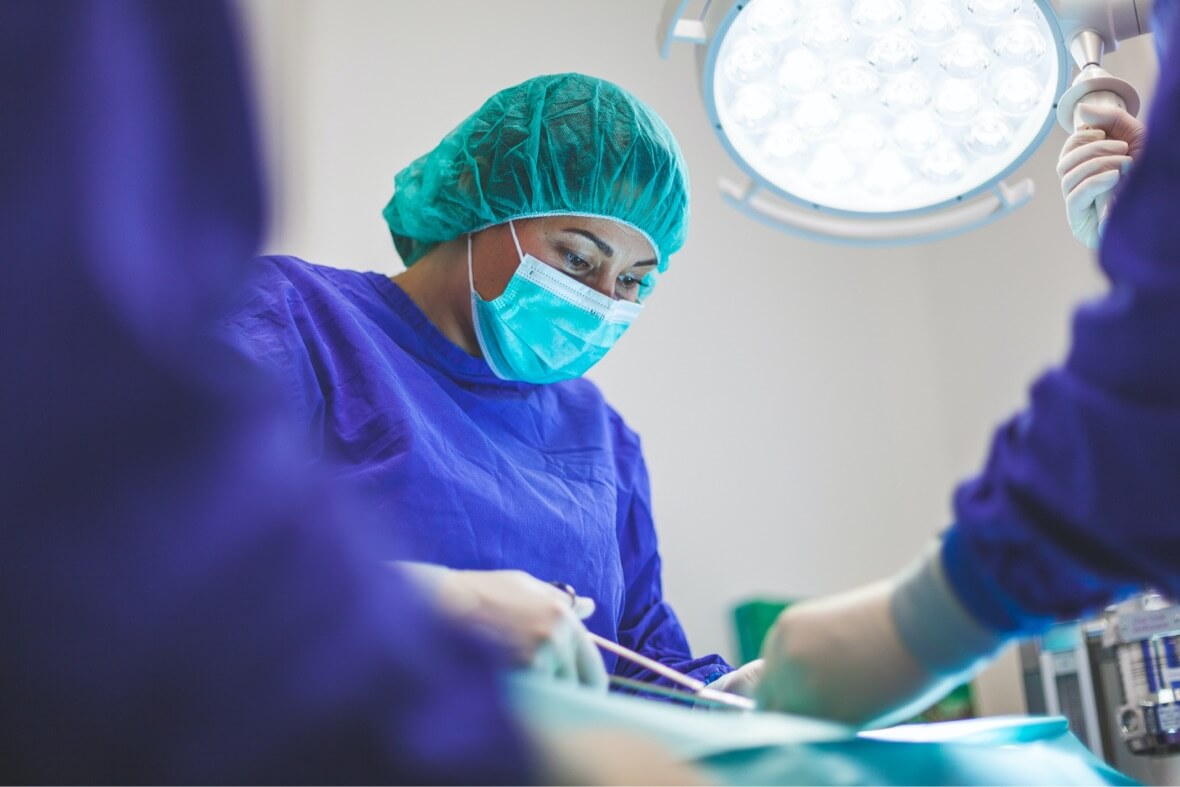 A surgeon holds a medical instrument over a patient in an operating room during a procedure.